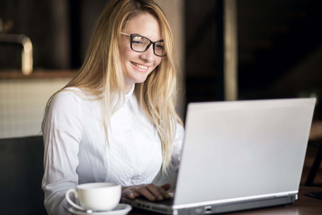 femme blonde travaille sur son ordinateur portable avec le sourire